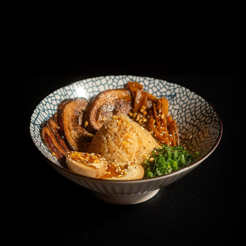A bowl of Frankie Ramen's rice, pork belly, marinated egg, and green onions.