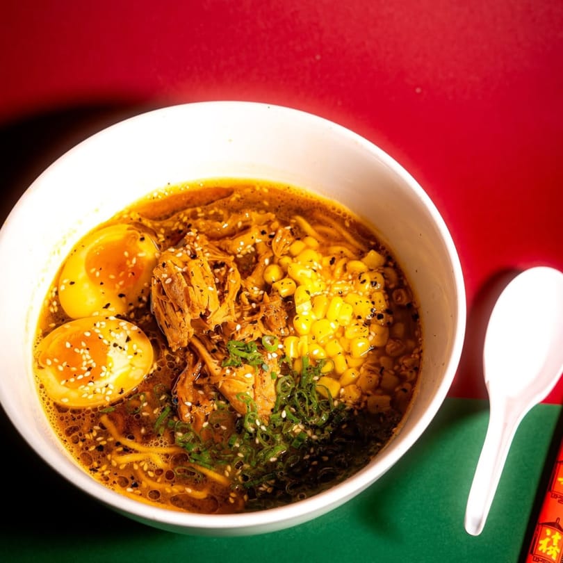 Frankie Ramen's ramen bowl with broth, noodles, corn, shredded chicken, and two soft-boiled eggs.